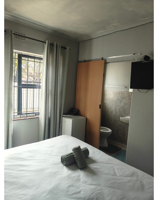 Guest room with en-suite bathroom, wall-mounted TV and bar fridge