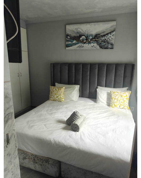 Double room with grey headboard, wardrobe and framed artwork